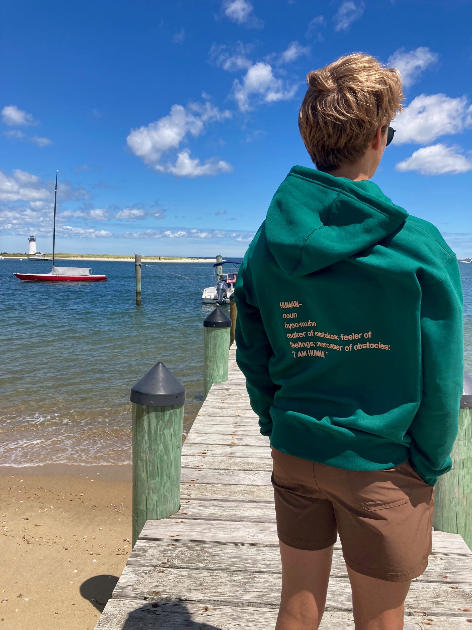 Back view of Robbie wearing green human definition hoodie in a size Medium.