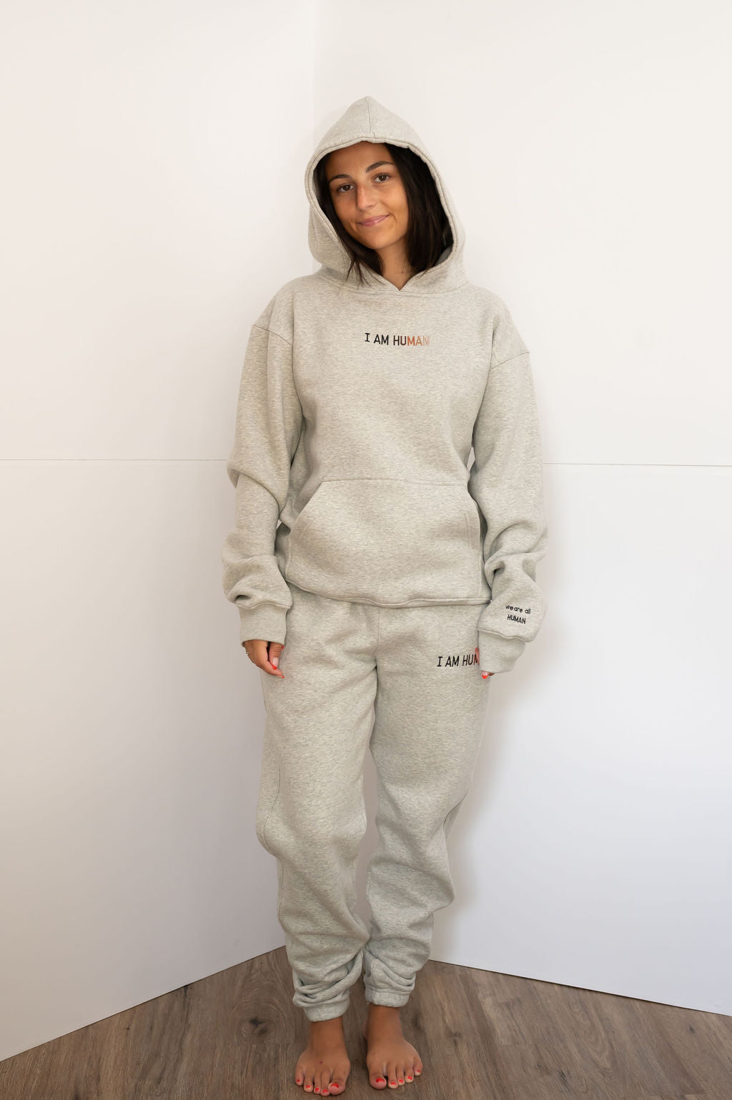 Front view of Elizabeth in I AM HUMAN logo hoodie with hood up.