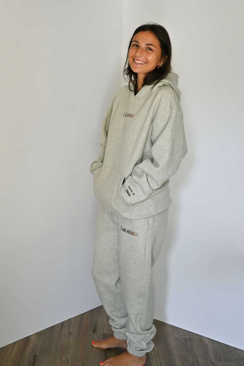 Side view of Elizabeth in I AM HUMAN logo joggers, the light grey color.