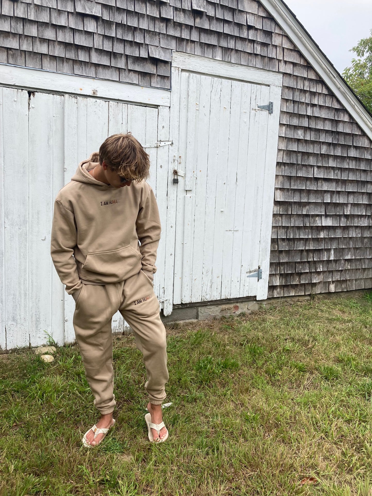 Robbie wearing medium logo joggers in tan.