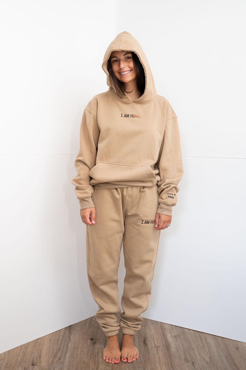 Front view of Elizabeth in medium tan I AM HUMAN logo hoodie. 