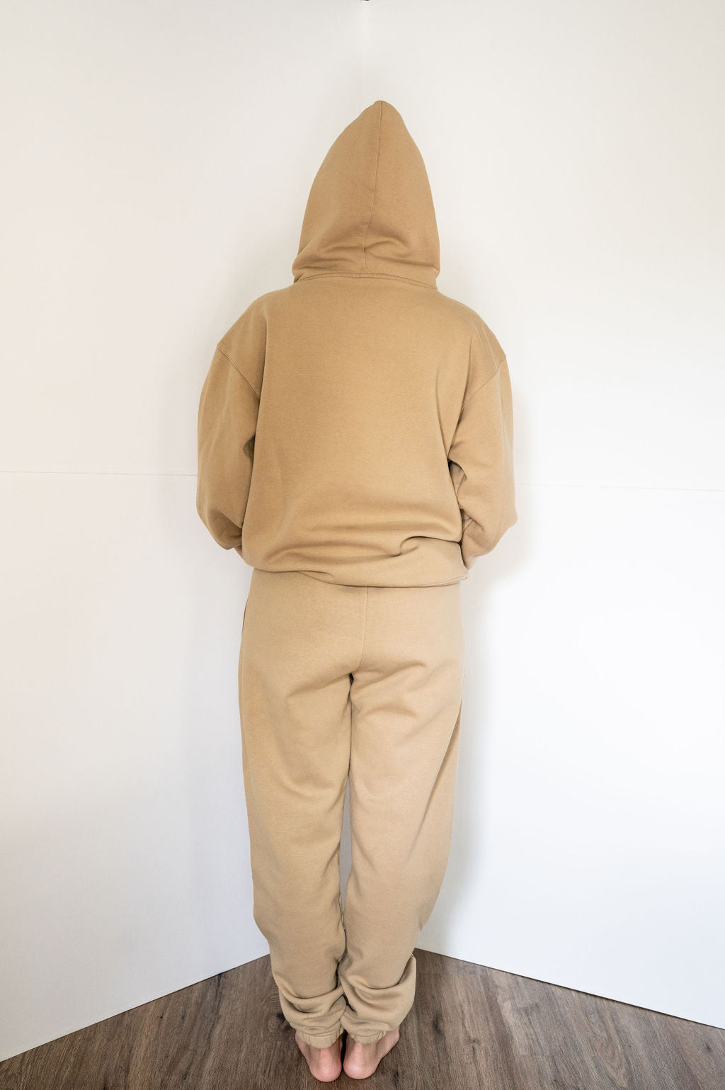 Back view of Elizabeth in tan logo hoodie. 