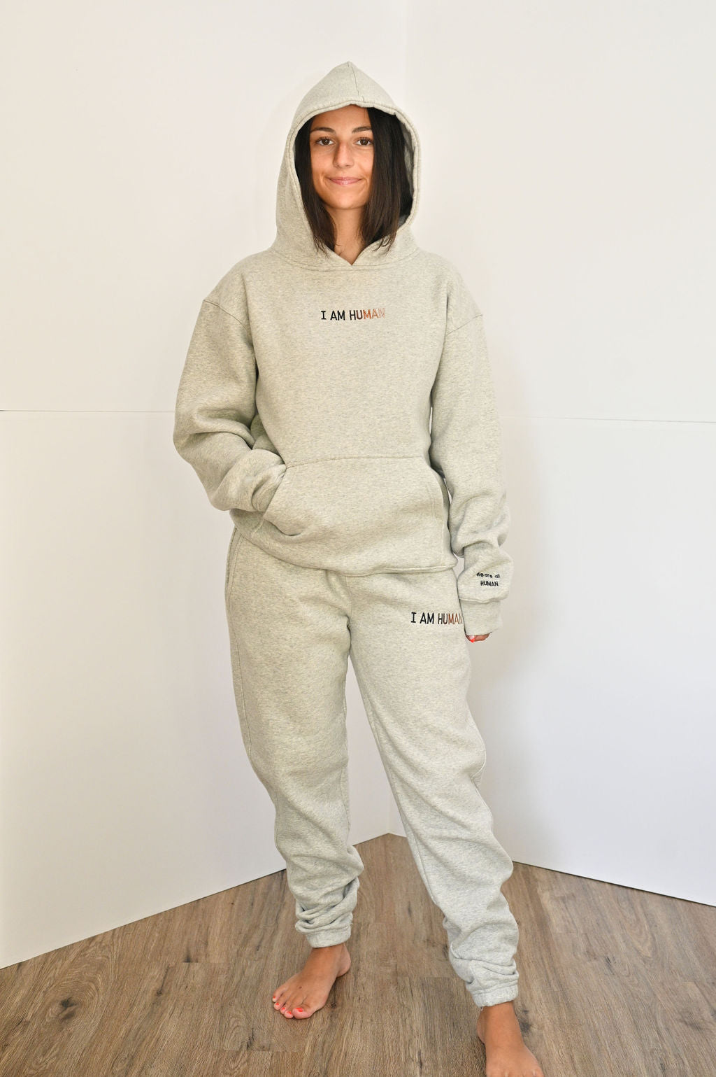 Elizabeth wears grey I AM HUMAN logo hoodie in size Medium. 