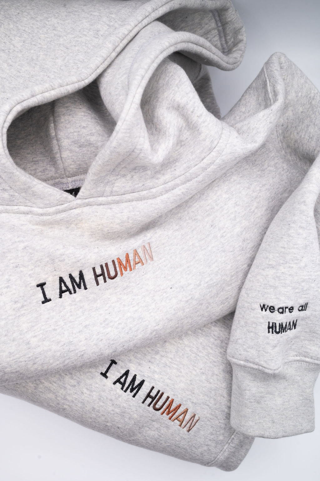 Close up of embroidered logo on chest and 'we are all human' on sleeve.