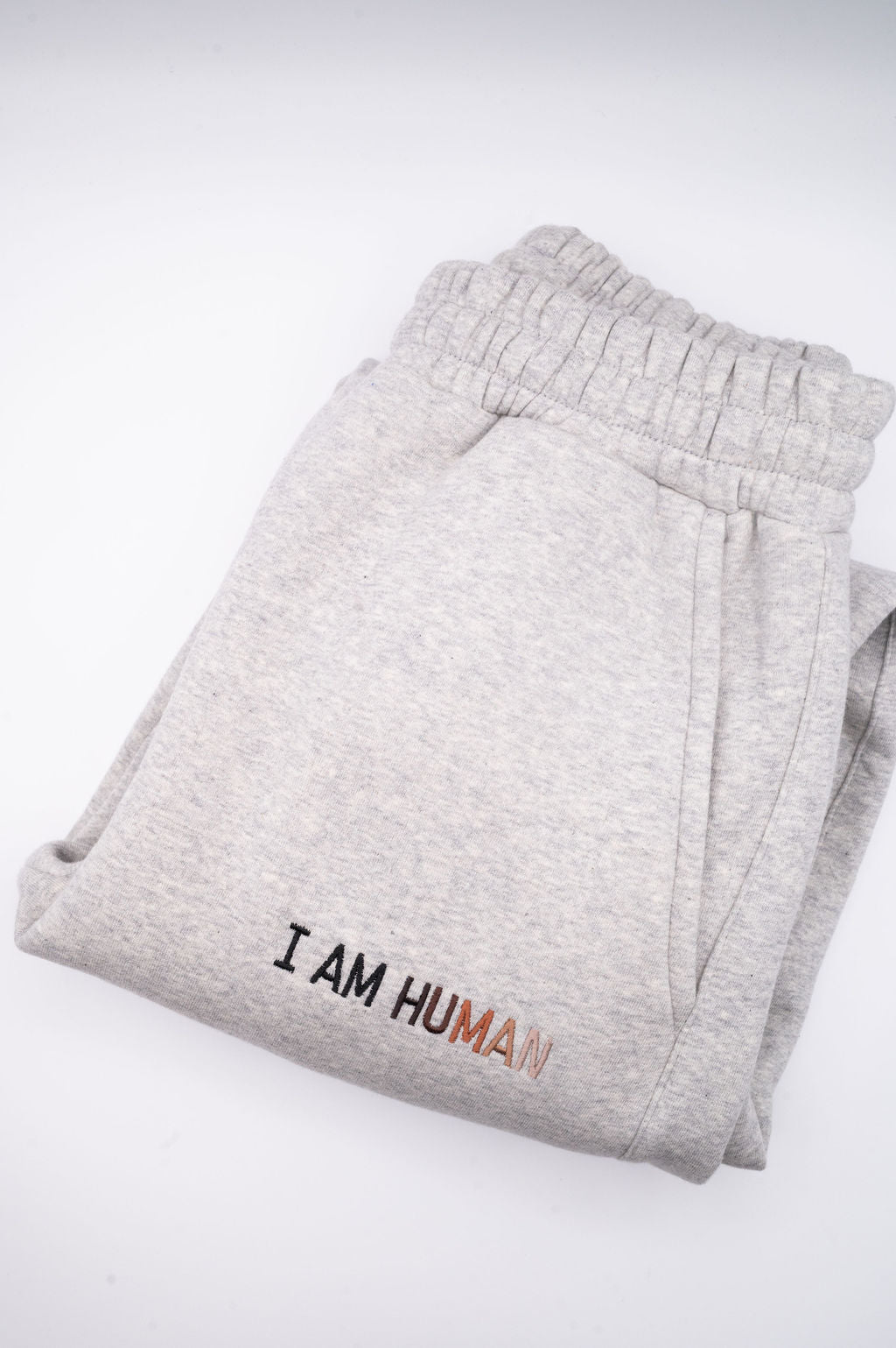 Folded pair of grey logo jogger showing the stretch waistband, pockets, and embroidered logo. 